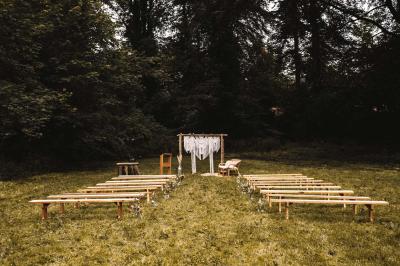 Salle de réception élégante avec tables dressées, chaises blanches, décorations florales et un piano en arrière-plan.