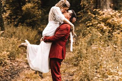 Salle de réception élégante avec tables dressées, chaises blanches, décorations florales et un piano en arrière-plan.