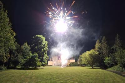 Salle de réception élégante avec tables dressées, chaises blanches, décorations florales et un piano en arrière-plan.
