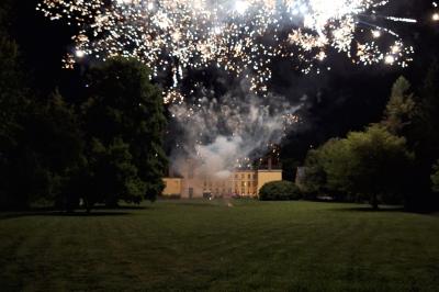 Salle de réception élégante avec tables dressées, chaises blanches, décorations florales et un piano en arrière-plan.