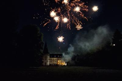 Salle de réception élégante avec tables dressées, chaises blanches, décorations florales et un piano en arrière-plan.