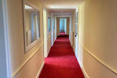 Salle de réception élégante avec tables dressées, chaises blanches, décorations florales et un piano en arrière-plan.