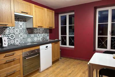 Salle de réception élégante avec tables dressées, chaises blanches, décorations florales et un piano en arrière-plan.