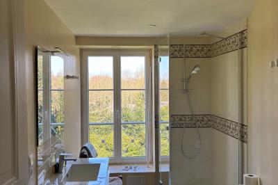 Salle de réception élégante avec tables dressées, chaises blanches, décorations florales et un piano en arrière-plan.