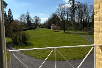 Salle de réception élégante avec tables dressées, chaises blanches, décorations florales et un piano en arrière-plan.