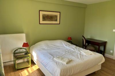 Salle de réception élégante avec tables dressées, chaises blanches, décorations florales et un piano en arrière-plan.