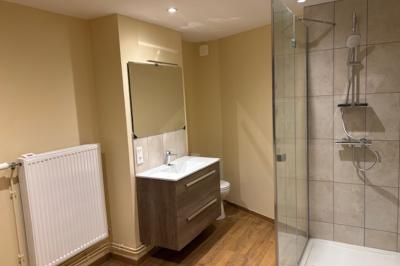 Salle de réception élégante avec tables dressées, chaises blanches, décorations florales et un piano en arrière-plan.