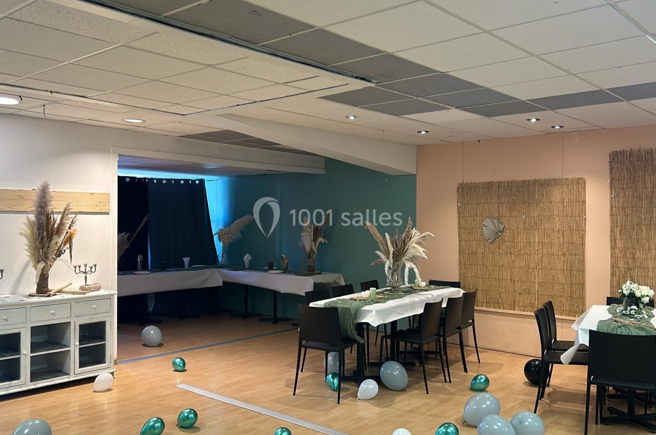 Salle décorée pour un événement avec tables dressées, ballons au sol et ornements en herbes séchées.