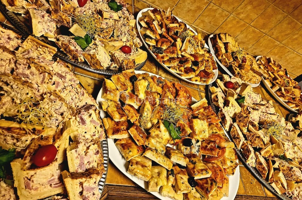 Plateaux variés de bouchées salées, incluant pizzas, quiches et tartes, présentés sur une table en intérieur.