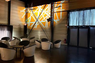 Terrasse extérieure avec tables, chaises et parasols, située près d'un bâtiment moderne et d'un espace vert.