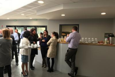Terrasse extérieure avec tables, chaises et parasols, située près d'un bâtiment moderne et d'un espace vert.