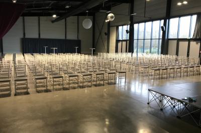 Terrasse extérieure avec tables, chaises et parasols, située près d'un bâtiment moderne et d'un espace vert.