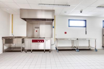 Terrasse extérieure avec tables, chaises et parasols, située près d'un bâtiment moderne et d'un espace vert.