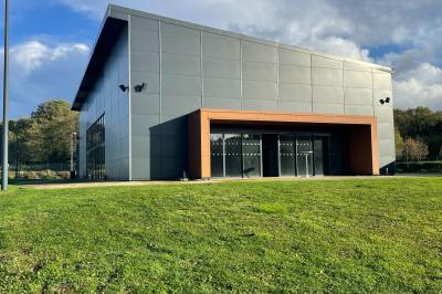Terrasse extérieure avec tables, chaises et parasols, située près d'un bâtiment moderne et d'un espace vert.