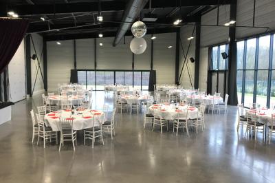 Terrasse extérieure avec tables, chaises et parasols, située près d'un bâtiment moderne et d'un espace vert.