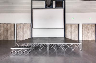 Terrasse extérieure avec tables, chaises et parasols, située près d'un bâtiment moderne et d'un espace vert.