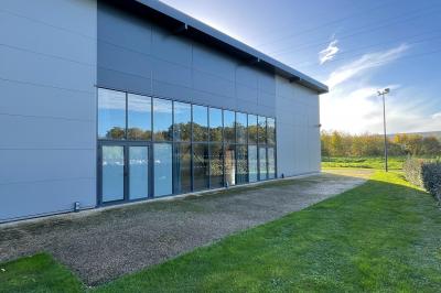 Terrasse extérieure avec tables, chaises et parasols, située près d'un bâtiment moderne et d'un espace vert.