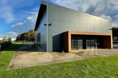 Terrasse extérieure avec tables, chaises et parasols, située près d'un bâtiment moderne et d'un espace vert.