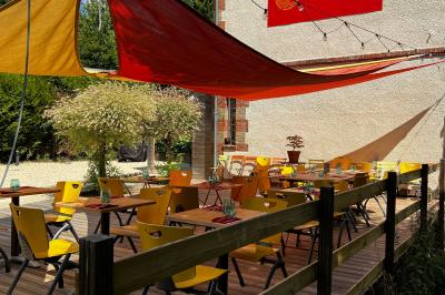 Banderole rouge annonçant l'ouverture d'un café, accrochée à une clôture en bois près d'un portail vert.