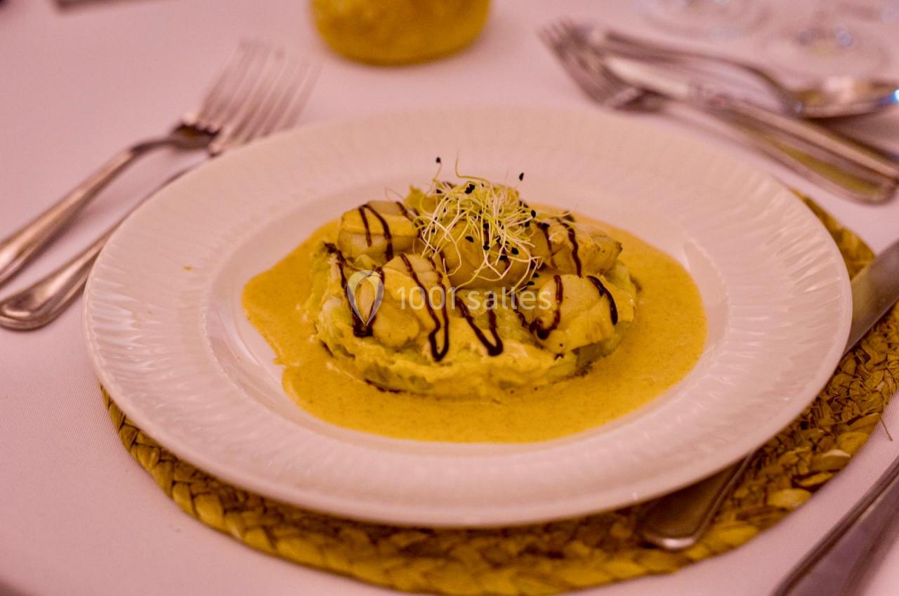 Assiette de ravioles nappées de sauce crémeuse, décorées de pousses et d'un filet de sauce balsamique.