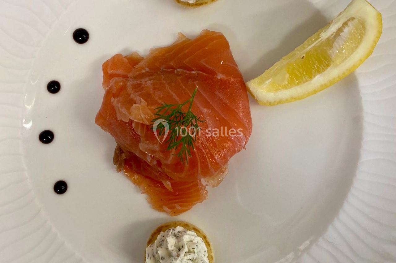 Assiette avec saumon fumé, citron, points de vinaigre balsamique et canapés garnis de fromage frais aux herbes.