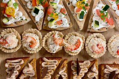 Plateau de verrines et amuse-bouches colorés disposés sur une planche en bois, en extérieur sur une pelouse.