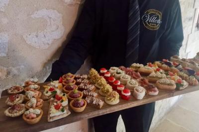 Plateau de verrines et amuse-bouches colorés disposés sur une planche en bois, en extérieur sur une pelouse.