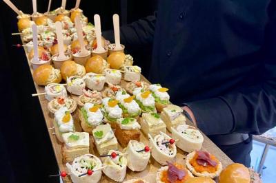 Plateau de verrines et amuse-bouches colorés disposés sur une planche en bois, en extérieur sur une pelouse.
