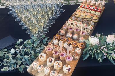 Plateau de verrines et amuse-bouches colorés disposés sur une planche en bois, en extérieur sur une pelouse.