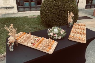 Plateau de verrines et amuse-bouches colorés disposés sur une planche en bois, en extérieur sur une pelouse.
