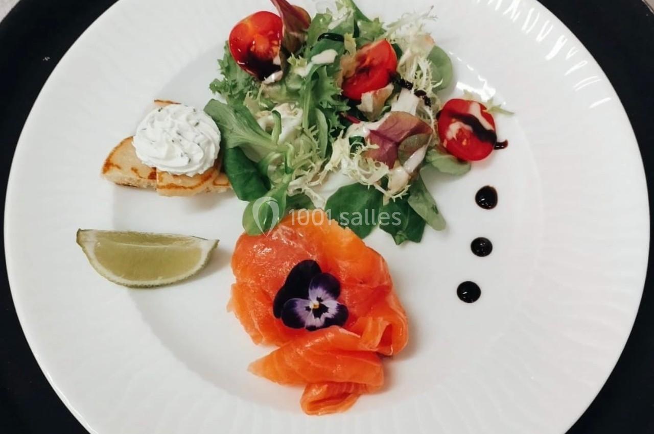 Assiette composée de saumon fumé, salade verte, toast garni, quartier de citron et décorations de sauce balsamique.