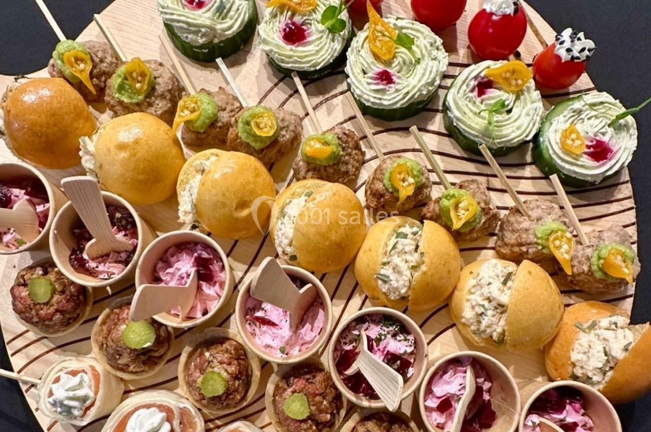 Plateau de bouchées apéritives variées comprenant mini-burgers, verrines, brochettes et amuse-bouches colorés.