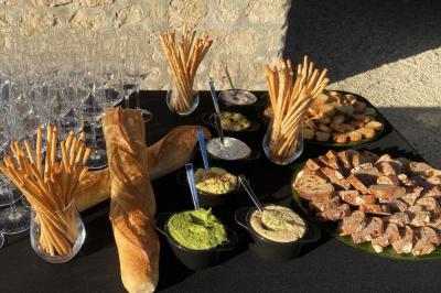 Plateau de verrines et amuse-bouches colorés disposés sur une planche en bois, en extérieur sur une pelouse.