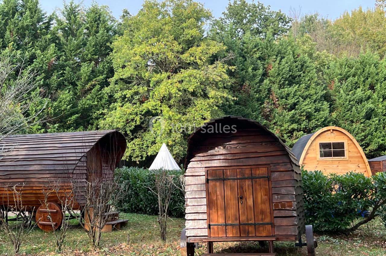 Roulottes en bois installées dans un espace naturel entouré d'arbres et de végétation.