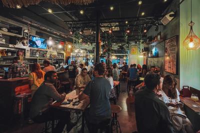 Deux personnes souriantes dans un café à l'ambiance chaleureuse, avec un mur en briques et une enseigne néon.
