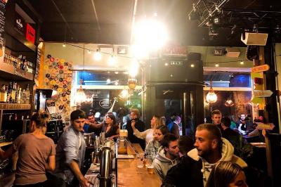 Deux personnes souriantes dans un café à l'ambiance chaleureuse, avec un mur en briques et une enseigne néon.