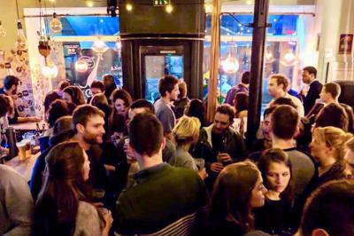 Deux personnes souriantes dans un café à l'ambiance chaleureuse, avec un mur en briques et une enseigne néon.