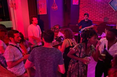 Deux personnes souriantes dans un café à l'ambiance chaleureuse, avec un mur en briques et une enseigne néon.