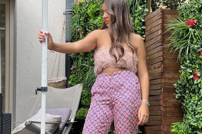 Miniature Pretty Women #2 Femme souriante portant une jupe argentée scintillante et une chemise blanche, debout sur une structure métallique en…