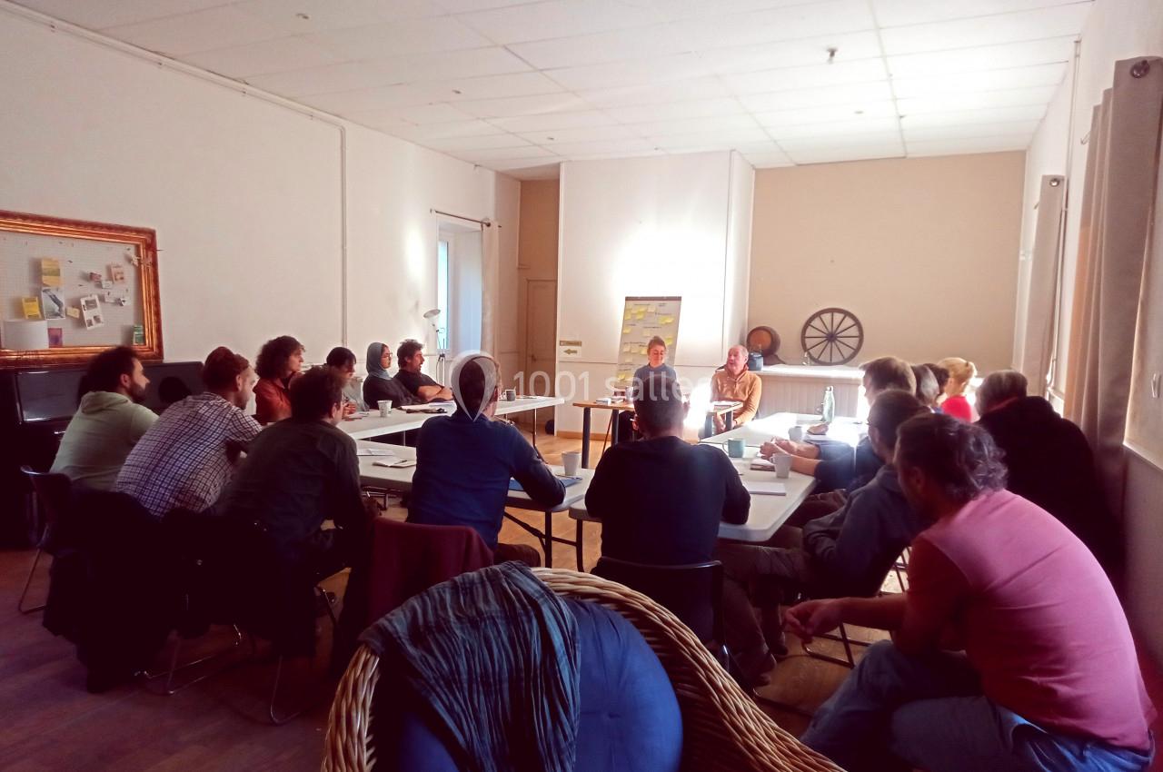 Un groupe de personnes assises autour de tables en réunion dans une salle lumineuse.