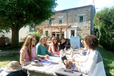 Salon chaleureux avec fauteuils en rotin, canapé, poêle à bois, bibliothèque et lumière naturelle.