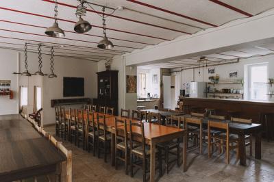Salon chaleureux avec fauteuils en rotin, canapé, poêle à bois, bibliothèque et lumière naturelle.