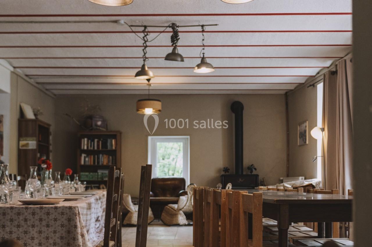 Salle à manger lumineuse avec tables dressées, chaises en bois et lampes suspendues, ambiance chaleureuse.