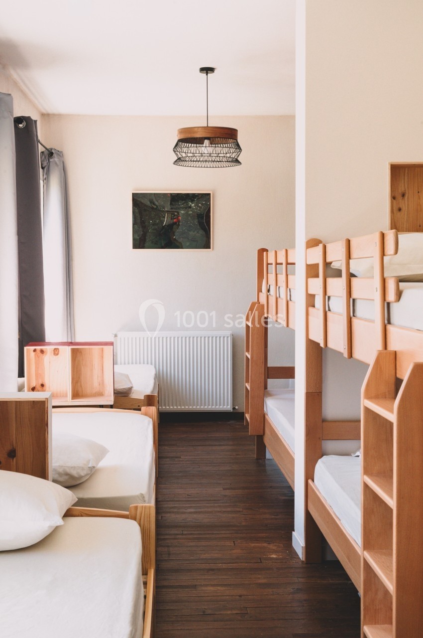 Chambre avec lits superposés en bois, parquet au sol, lumière naturelle et décoration minimaliste.