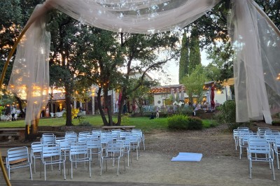 Décoration de table élégante sous un plafond de guirlandes lumineuses et de toile de jute en soirée extérieure.