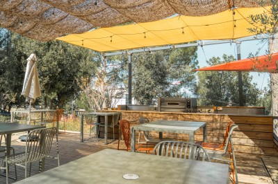 Décoration de table élégante sous un plafond de guirlandes lumineuses et de toile de jute en soirée extérieure.