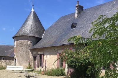Chambre lumineuse avec un lit double, un canapé, un bureau en bois et une fenêtre donnant sur un espace vert.
