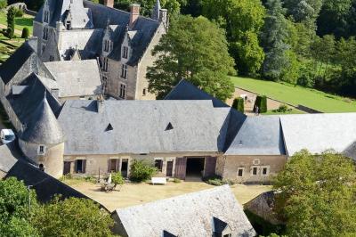 Chambre lumineuse avec un lit double, un canapé, un bureau en bois et une fenêtre donnant sur un espace vert.
