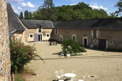 Chambre lumineuse avec un lit double, un canapé, un bureau en bois et une fenêtre donnant sur un espace vert.