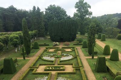 Chambre lumineuse avec un lit double, un canapé, un bureau en bois et une fenêtre donnant sur un espace vert.
